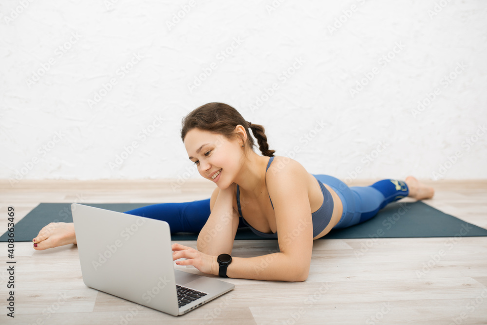 girl goes in for sports on the carpet at home with a computer