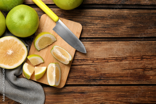 Flat lay composition with whole and cut sweetie fruits on wooden table, space for text photo