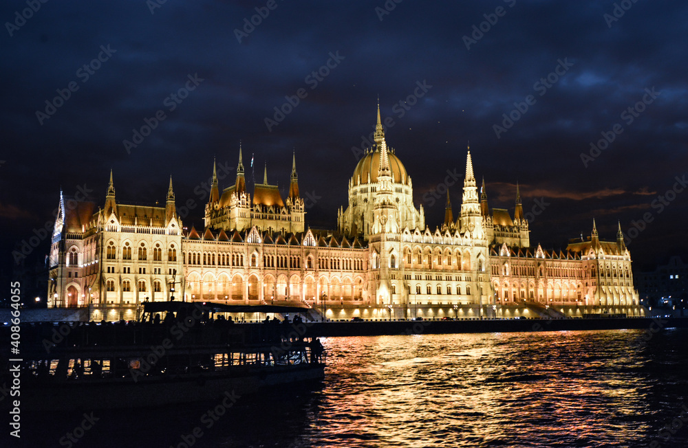 Late night shot of the Budapest Parliament building illuminated as a tourist boat is seen in shadow in front in Budapest, Hungary.