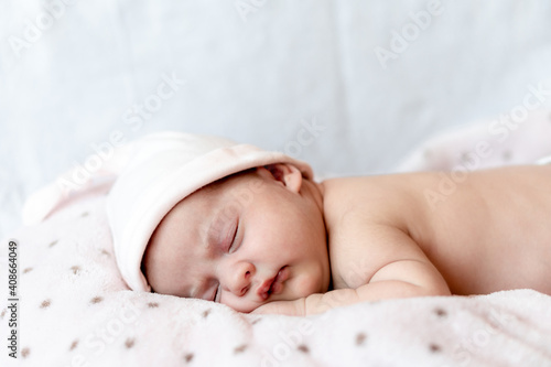 Childhood, care, motherhood, health, medicine, pediatrics concepts - Close up Little peace calm naked infant newborn baby girl in pink hat sleeps resting take deep nap laying on tummy on soft bed.