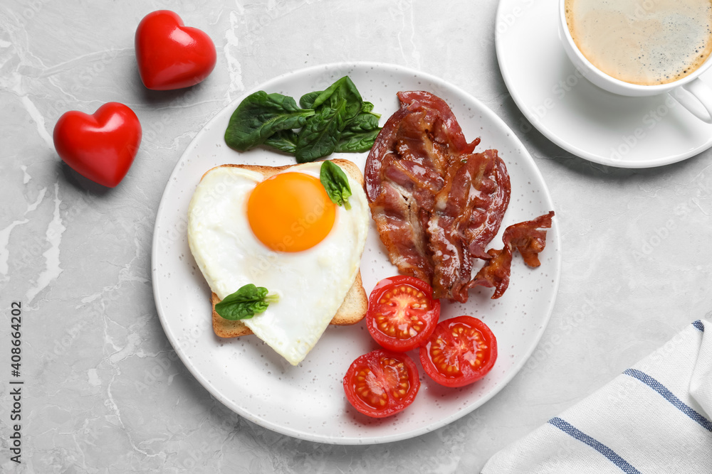 Romantic breakfast with fried bacon and heart shaped egg on grey table, flat lay. Valentine's day celebration Romantic breakfast with fried bacon and heart shaped egg on grey table, flat lay. Valentine's day celebration