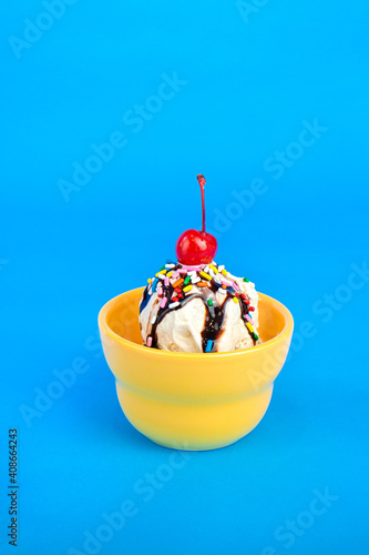 Ice cream sundae with cherry on top in yellow bowl 