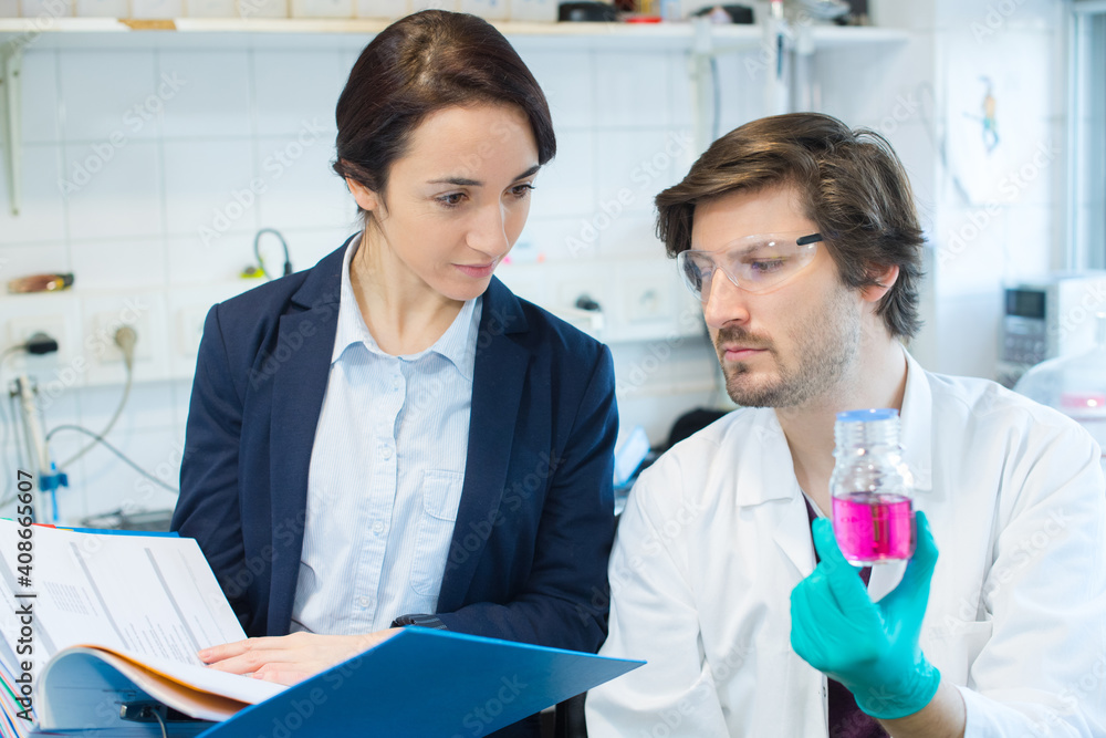 Obraz premium scientist holding beaker of pink liquid with woman holding folder