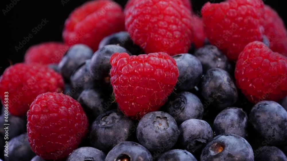 Raspberries and blueberries rotating on a black background close up, view. Fresh, firm and tasty berries with mint in 4K. Raw vegan summer snacks, forest berries. Raspberries and blueberries rotating on a black background close up, view. Fresh, firm and tasty berries with mint in 4K. Raw vegan summer snacks, forest berries.