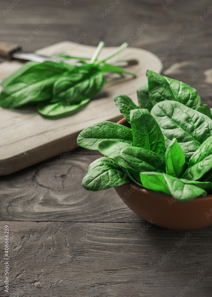 Fresh spinach leaves in a bowl on a rustic wooden table. Selective focus. Fresh spinach leaves in a bowl on a rustic wooden table. Selective focus.