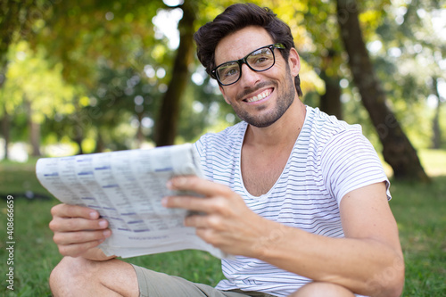 man sat on the grass reading a newspaper