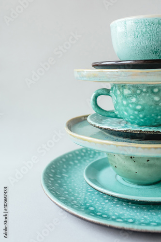 Vertical composition from a handmade turquoise plate and mug on gray background.