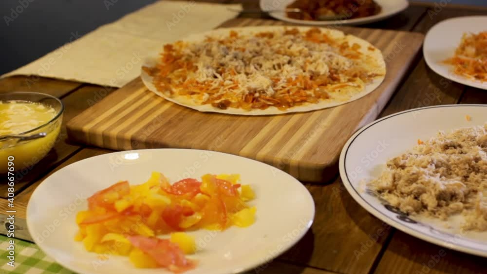 close-up of the hands, sprinkle the filling on the pizza dough. the family prepares food in the kitchen close-up of the hands, sprinkle the filling on the pizza dough. the family prepares food in the kitchen