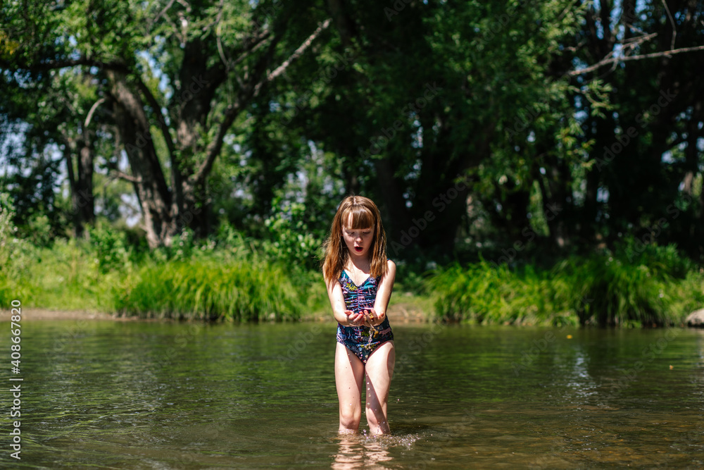 Excited young girl playing in a creek on a sunny day Excited young girl playing in a creek on a sunny day