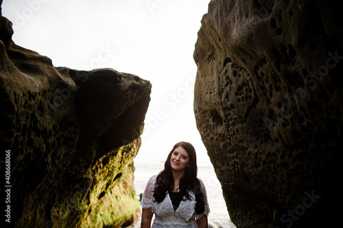 Newlywed Bride Standing Between Rocks on Beach in San Diego photo