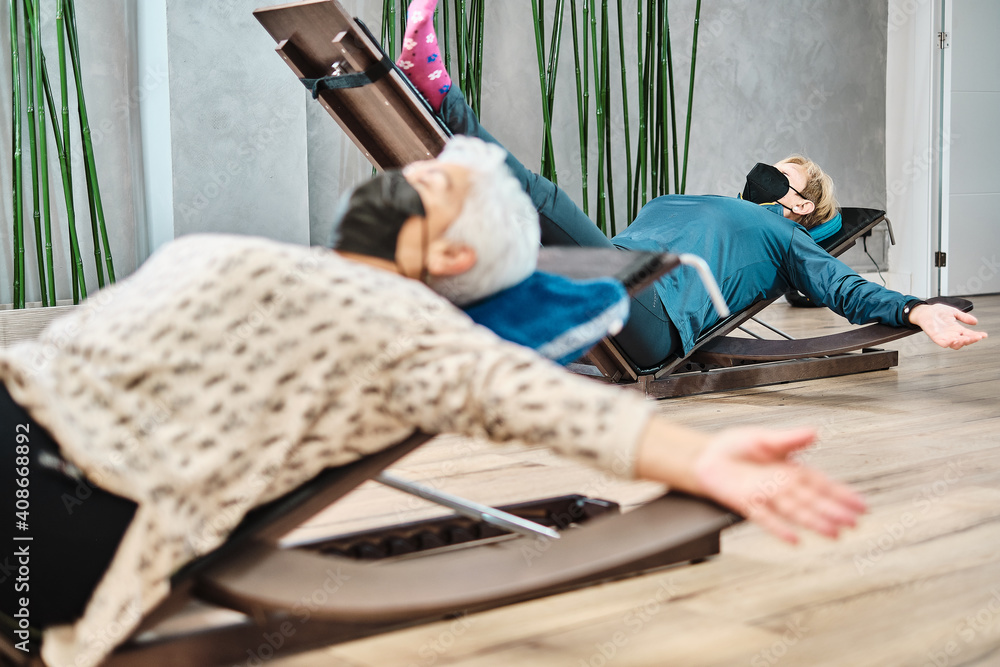 Fototapeta premium Old women lying down doing yoga exercises in a physiotherapy