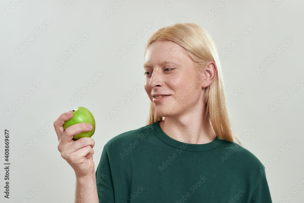 Smiling young caucasian man looking at green juicy apple Smiling young caucasian man looking at green juicy apple