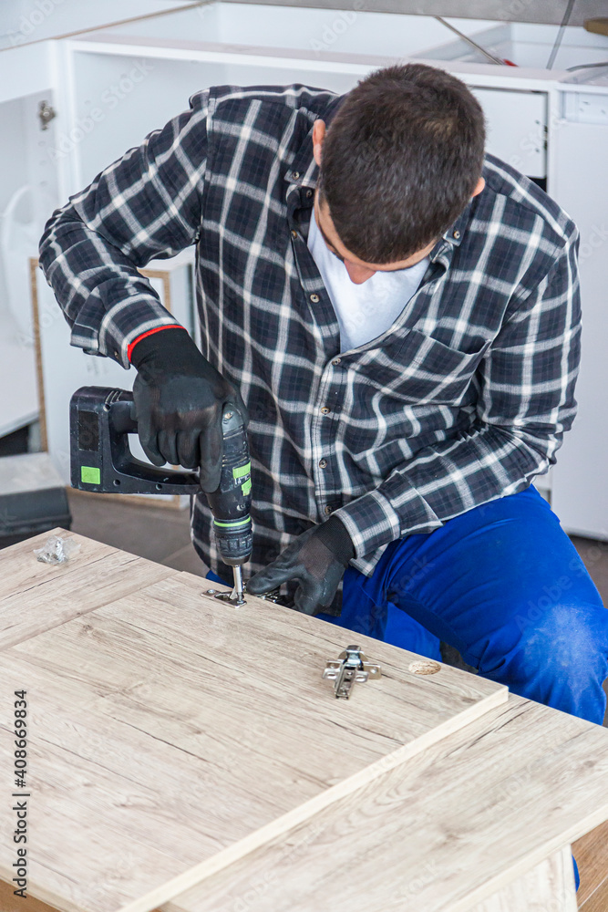 The carpenter finalizing the assembly of the kitchen shelf