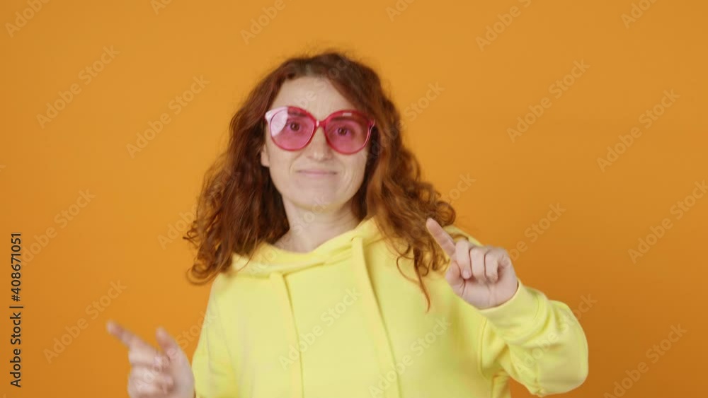 Dances Happy Young Woman Joyfully, Long Red Hair Develops from side to Side Yellow Background, shakes her Head and Rhythmically Moves Her Hands to Music Sings Slow Motion. Positive Emotion. Freedom Dances Happy Young Woman Joyfully, Long Red Hair Develops from side to Side Yellow Background, shakes her Head and Rhythmically Moves Her Hands to Music Sings Slow Motion. Positive Emotion. Freedom