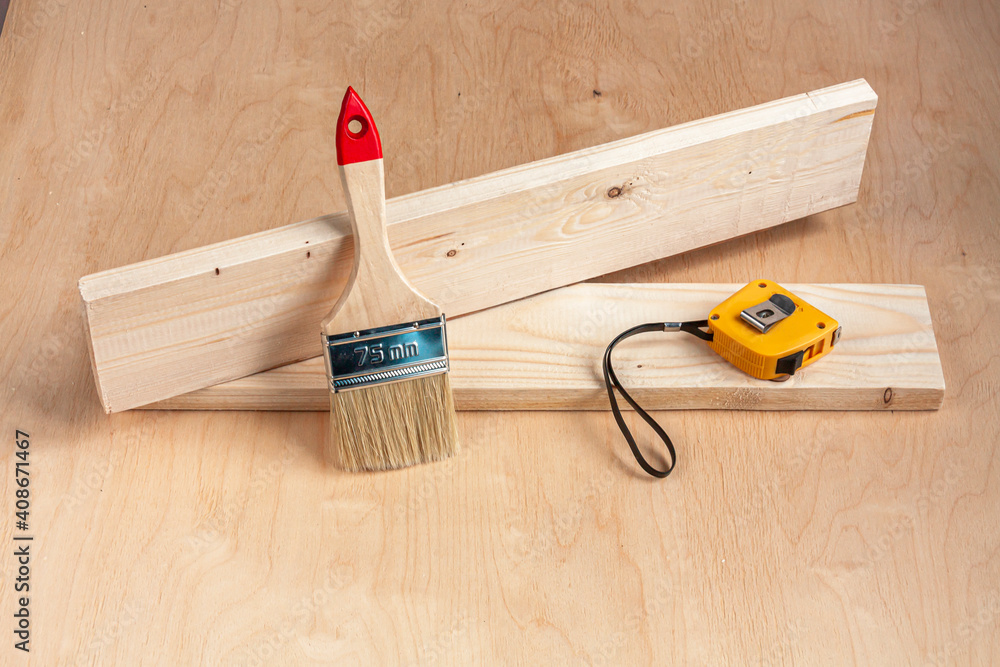 a paintbrush and a tape measure on wood boards on wooden background a paintbrush and a tape measure on wood boards on wooden background