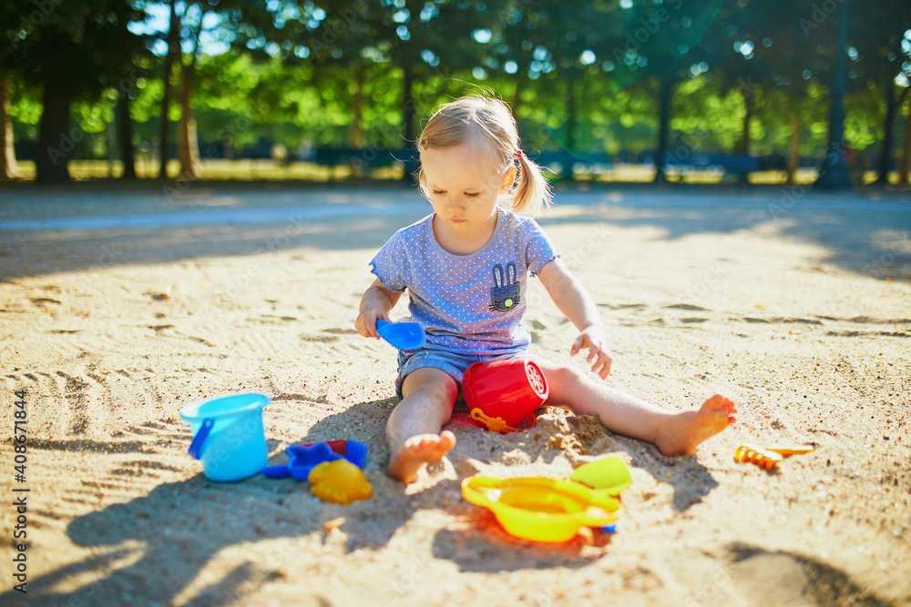 Adorable little girl having fun on playground in sandpit Adorable little girl having fun on playground in sandpit