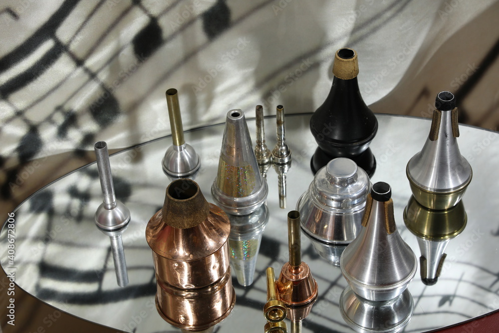 Lots of mutes and mouthpieces for musical instruments on a mirrored surface with reflection. Display of a collection of trumpet accessories.The concept of passion for music.Background Lots of mutes and mouthpieces for musical instruments on a mirrored surface with reflection. Display of a collection of trumpet accessories.The concept of passion for music.Background