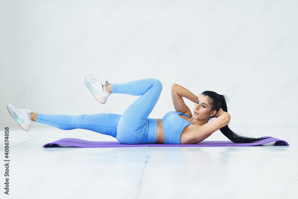 Young woman doing abs exercises in living room performing alternate leg raising and crunch exercise Young woman doing abs exercises in living room performing alternate leg raising and crunch exercise