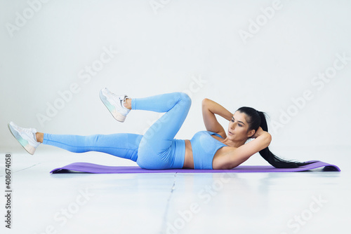 Young woman doing abs exercises in living room performing alternate leg raising and crunch exercise