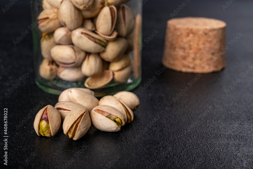 Pistachio nuts on a dark table. Salty snack in a jar. Pistachio nuts on a dark table. Salty snack in a jar.
