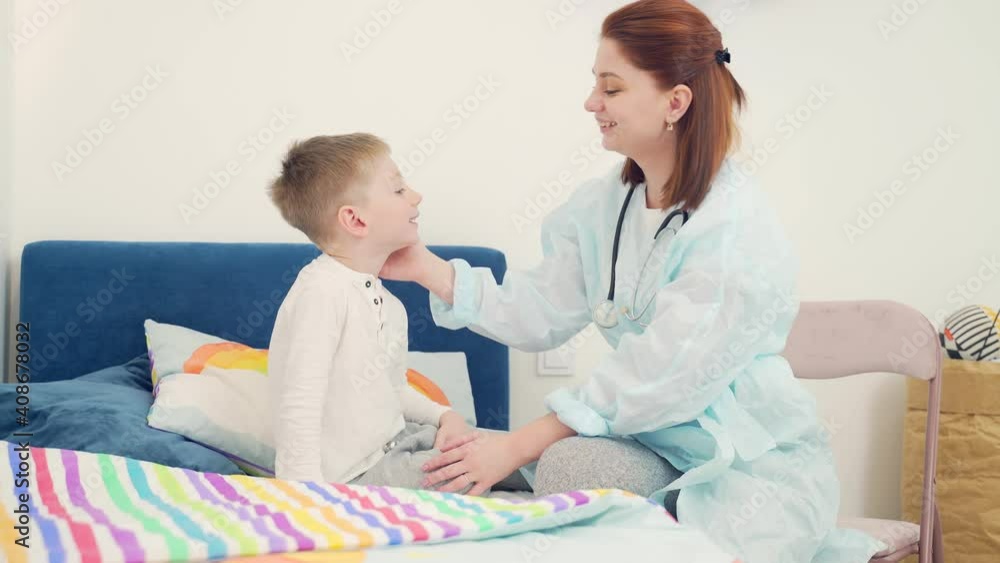 Friendly cheerful female pediatrician examines baby's throat and mouth at home. Family doctor examines a small child. Sick boy being examined by a female doctor Friendly cheerful female pediatrician examines baby's throat and mouth at home. Family doctor examines a small child. Sick boy being examined by a female doctor