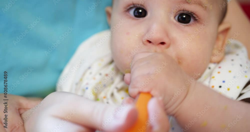 mother holds the baby in her arms and feeds her boy with a spoon. family, food, child, eating and parenthood concept mother holds the baby in her arms and feeds her boy with a spoon. family, food, child, eating and parenthood concept
