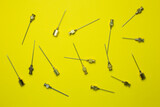 Set of old syringe needles in different sizes and thicknesses. Yellow background