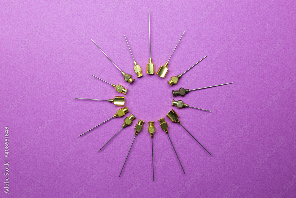 Obraz premium set of antique syringe needles of different sizes and thicknesses forming a circle in the shape of a coronavirus. Violet background