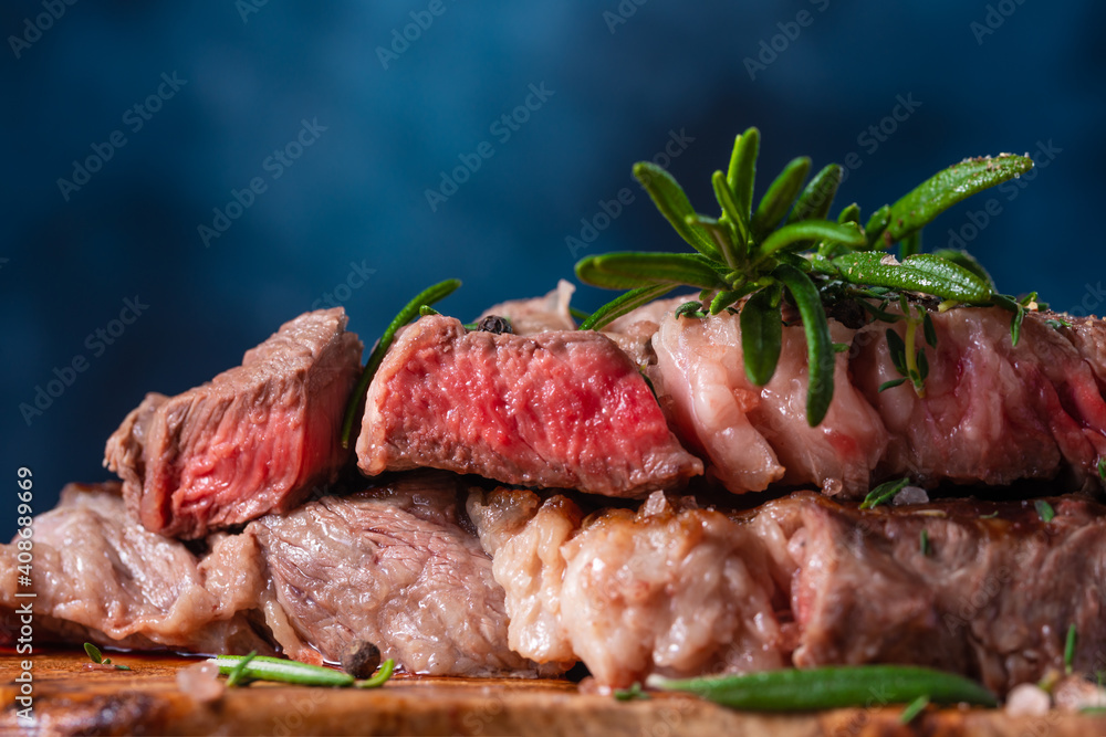 Rare steak with rosemary and seasoning and on a blue background. Fried meat. Tasty food. Recipe book and cooking. Orstration for culinary recipes