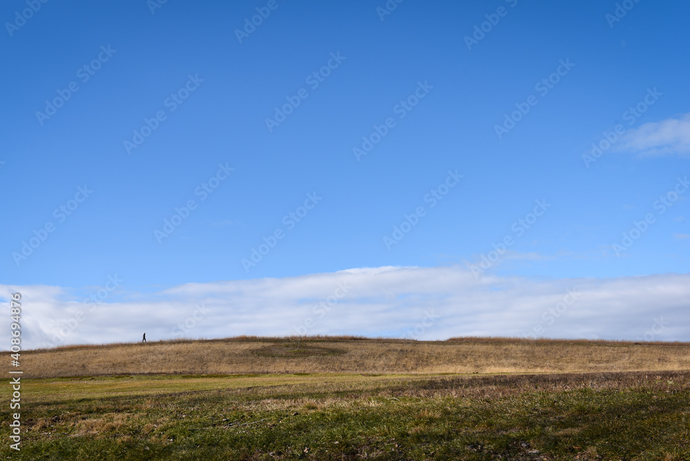 Wide angle shot of a man walking across a field.