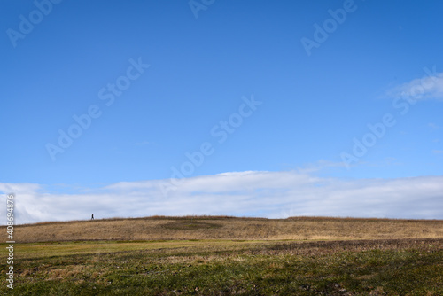 Wide angle shot of a man walking across a field. © Sean