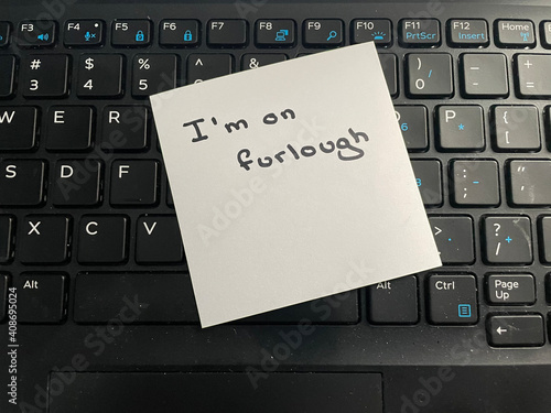 A handwritten note stating I'm on furlough on a computer keyboard