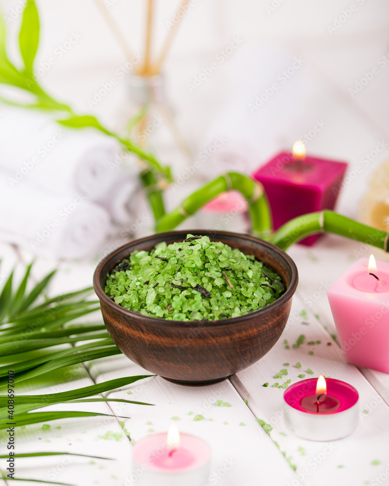 Spa. Green herbal spirulina salt in ceramic bowl, spa towels, pink scented candle and bamboo