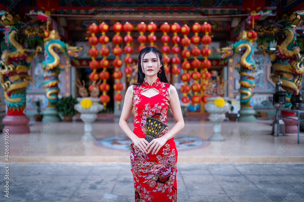 Portrait beautiful smiles Asian young woman wearing red traditional Chinese cheongsam decoration for Chinese New Year Festival at Chinese shrine in Thailand Portrait beautiful smiles Asian young woman wearing red traditional Chinese cheongsam decoration for Chinese New Year Festival at Chinese shrine in Thailand