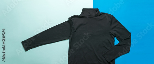 Men's dark sweater on a light and dark blue background.