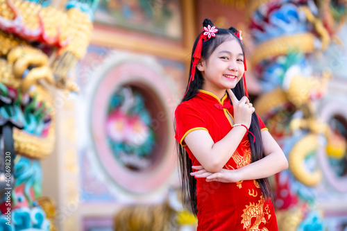 Portrait beautiful smiles Cute little Asian girl wearing red traditional Chinese cheongsam decoration for Chinese New Year Festival at Chinese shrine