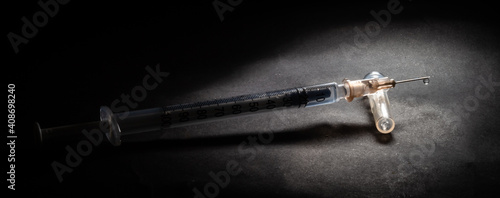 Vacina contra o Covid-19. Conceito dramático com Seringa para vacinação em fundo escuro.	 photo