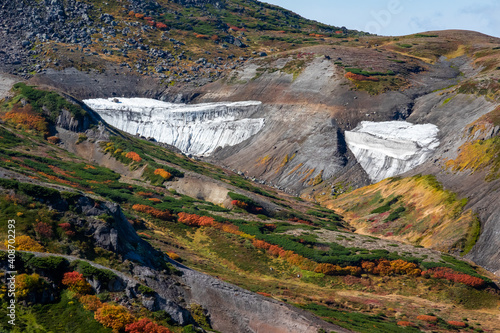 北海道の大雪山・赤岳山頂で見た、山頂周辺の紅葉が広がる風景と万年雪らしき白い物体、背景の青空