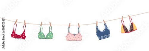 Modern female bra dried on a rope. Cute colorful brassieres after washing. Trendy undergarments. Vintage vector illustration in flat cartoon style. Suitable for logo, icon, banner.
