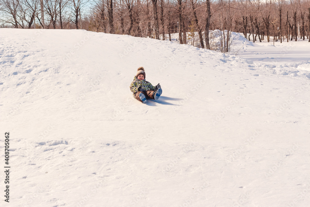 boy on sled ice rides from the hill in winter
