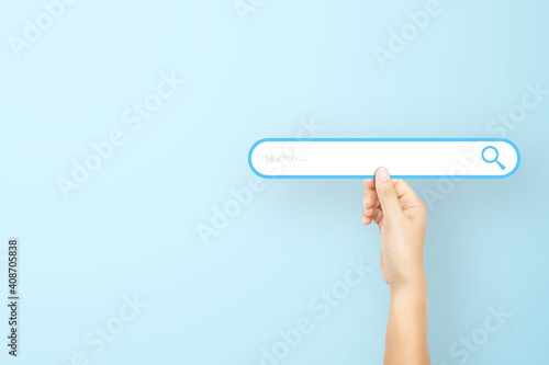 Hand holding paper with search bar on light blue background. Concept of searching information data on internet networking