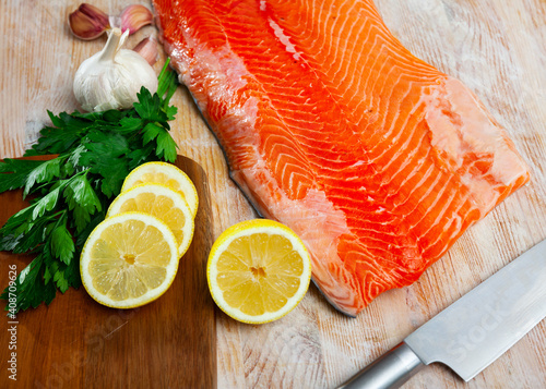 Image of appetizing raw salmon fillet with lemon and greens before cooking