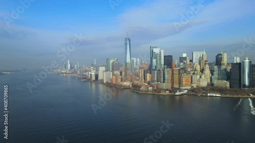 Aerial flying sideways above Hudson River overlooking beautiful downtown Manhattan skyline with stunning One World Trade Center and Battery Park on sunny summer day in New York City, USA.
