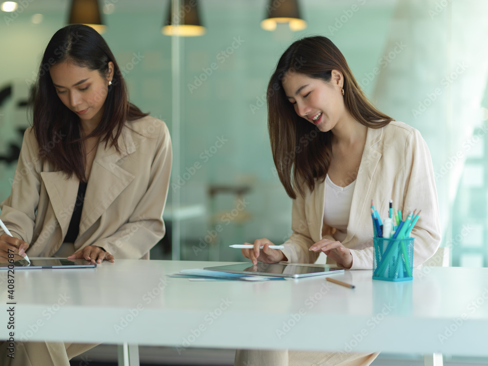 Two businesswomen working and talking to each other in office room Two businesswomen working and talking to each other in office room