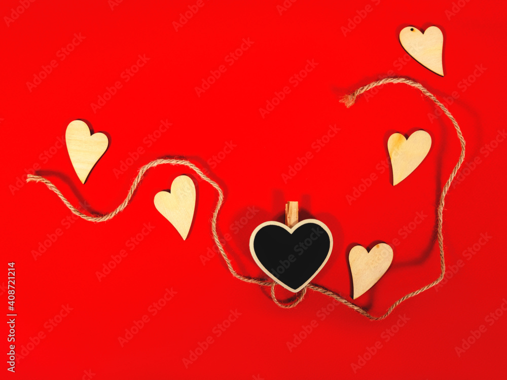St Valentine's concept as the wooden hearts and the rope on the red background with the space for your text. Flatlay.