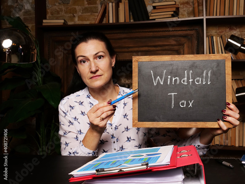 Businesswoman holding a black chalkboard. Business concept about Windfall Tax with phrase on the sheet.