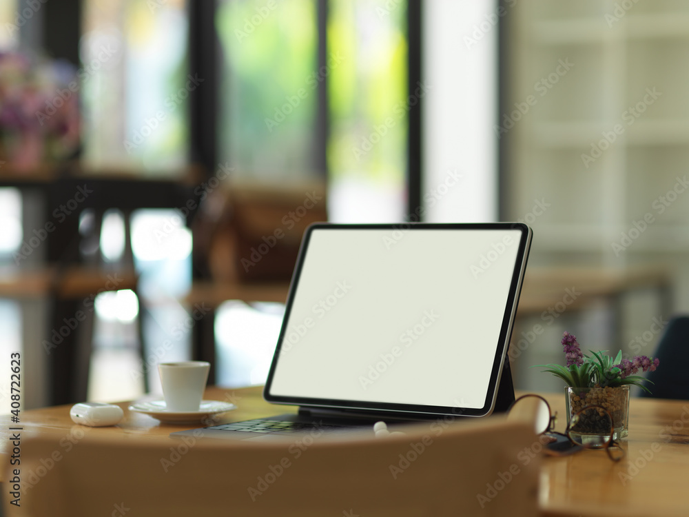 Wooden table with tablet, keyboard, eyeglasses, accessories and cup in home office Wooden table with tablet, keyboard, eyeglasses, accessories and cup in home office