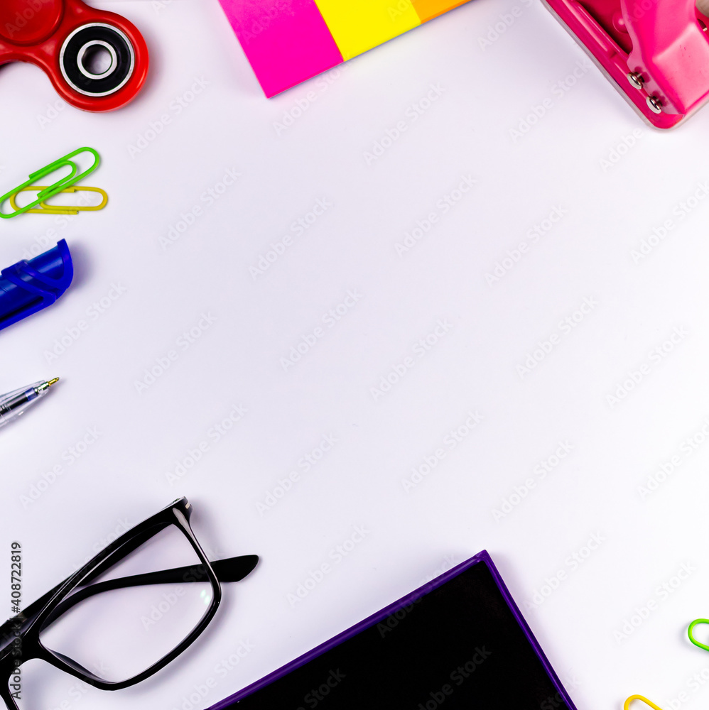 A red fidget spinner, sticky notes, paper punch, pens, stamp pad and eye  glasses over a white background. Stock-Foto | Adobe Stock