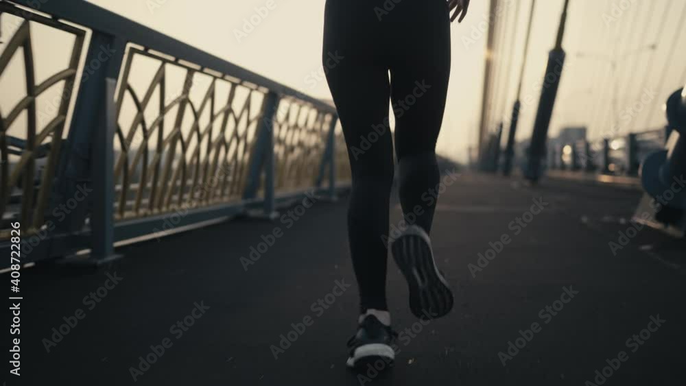 Follow camera angle from the side back. White skin Asian women wearing a black sports bra and black pants. Jogging on the bridge in the middle of the city In the morning or the evening Follow camera angle from the side back. White skin Asian women wearing a black sports bra and black pants. Jogging on the bridge in the middle of the city In the morning or the evening