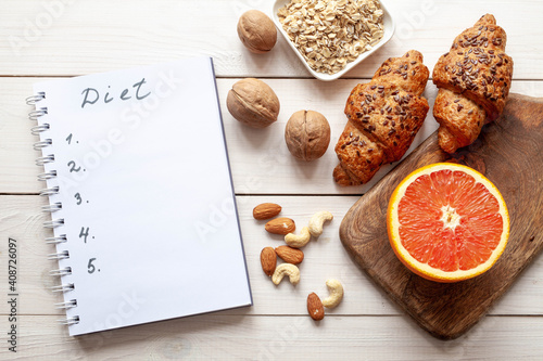 Diet plan on white wood background. Organic food: grapefruit, cereal, nuts and bakery products, top view